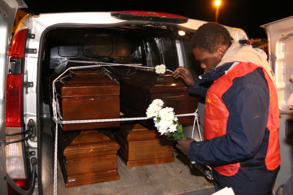 A man lays flowers on the coffins of immigrants who died trying to reach the Italian coast arrive from Lampedusa on 11 February, 2015.
© MARCELLO PATERNOSTRO/AFP/Getty Images