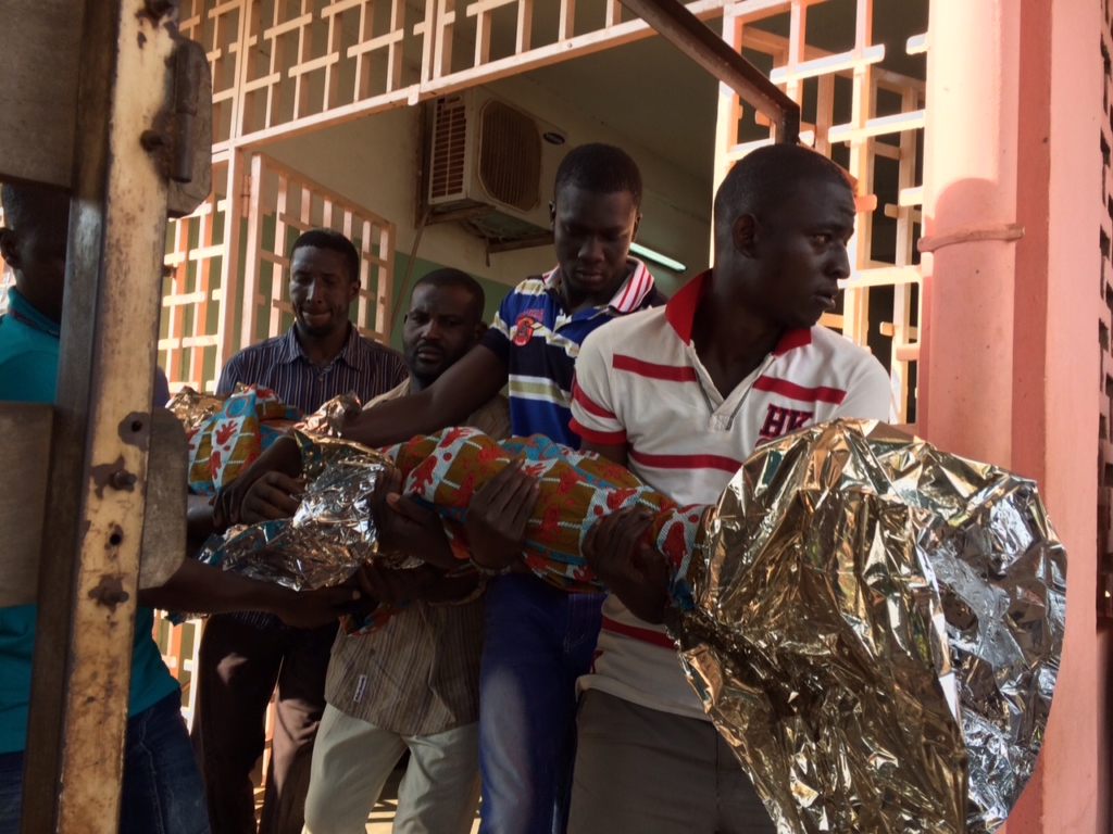 The body of Souleimane Hadji, 16, killed on 3 August 2015, is carried out of a hospital by his family.