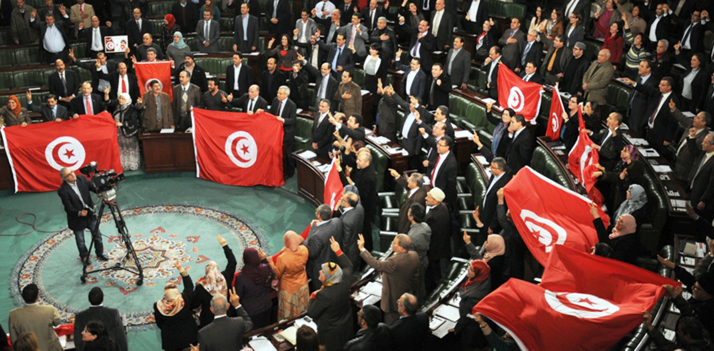 Deputies of the Tunisian National Constituent Assembly (NCA) with flags jubilate after the adoption of a new constitution on January 26, 2014, in Tunis. Tunisia's constituent assembly late on Sunday adopted a new constitution, more than three years after the revolution which began the Arab Spring. The assembly approved the constitution by an overwhelming majority, with 200 votes in favour, 12 against and four abstentions a live television broadcast showed. AFP PHOTO / STR (Photo credit should read STR/AFP/Getty Images)