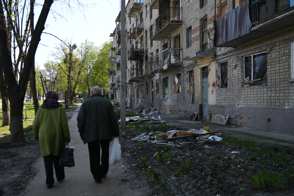 Residents walk past a building damaged in a multiple rocket strike in Nova Bavariya Avenue which killed at least seven people and injured 70 others on 1 March.