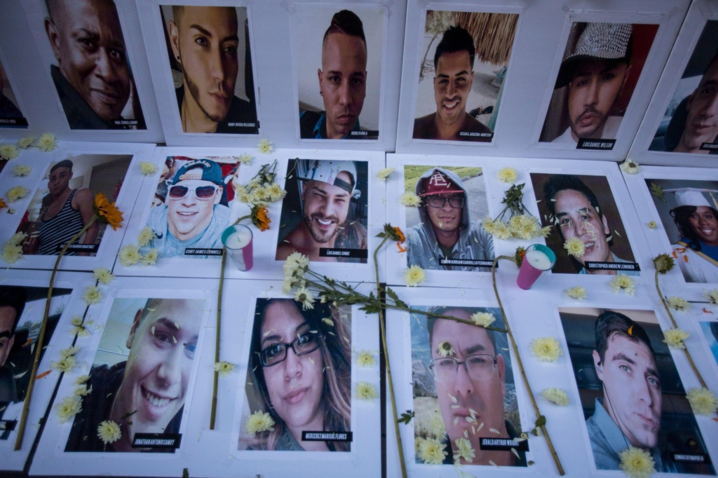 photos of people who were killed during the Pulse shooting lay across the ground. People have left candles and flowers on them to honour their memory.
