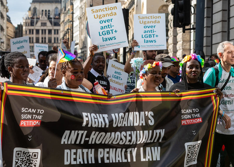 People march with a large black banner saying 'fight Uganda's anti-homosexuality death penalty law'. 