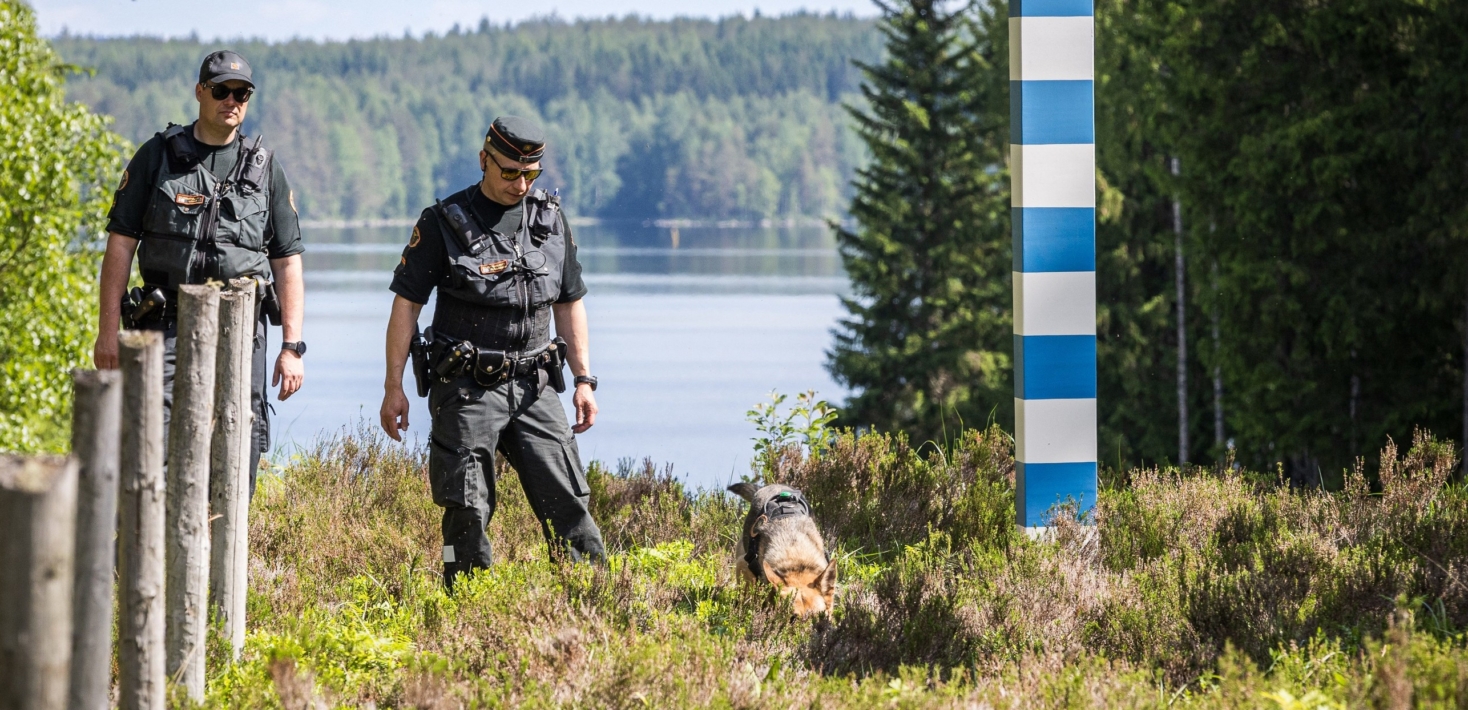 Finnish border guards with a dog in the forest by a lake