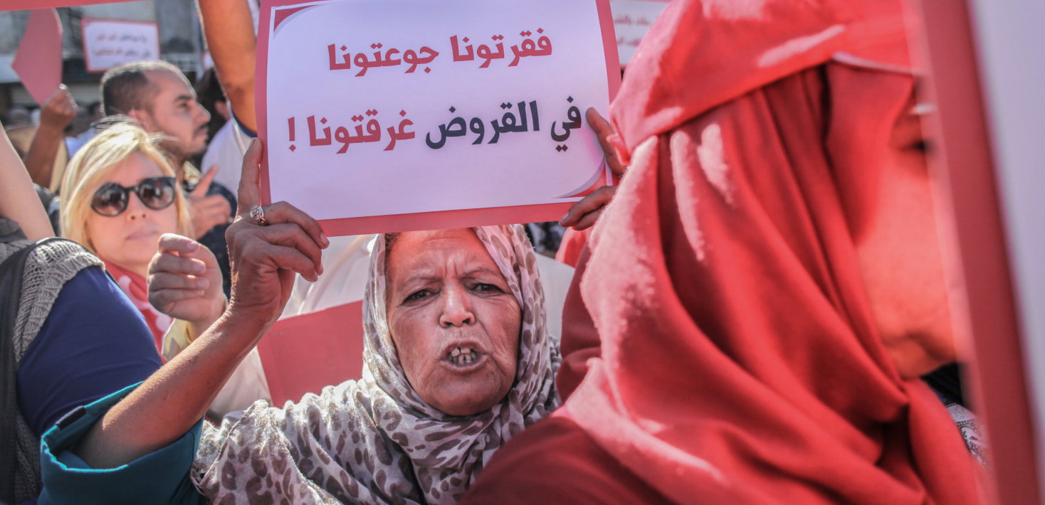 A woman at a protest in Tunisia holds up a sign saying: "you have impoverished us, starved us, drowned us in debts" Chedly Ben Ibrahim/NurPhoto via Getty Images