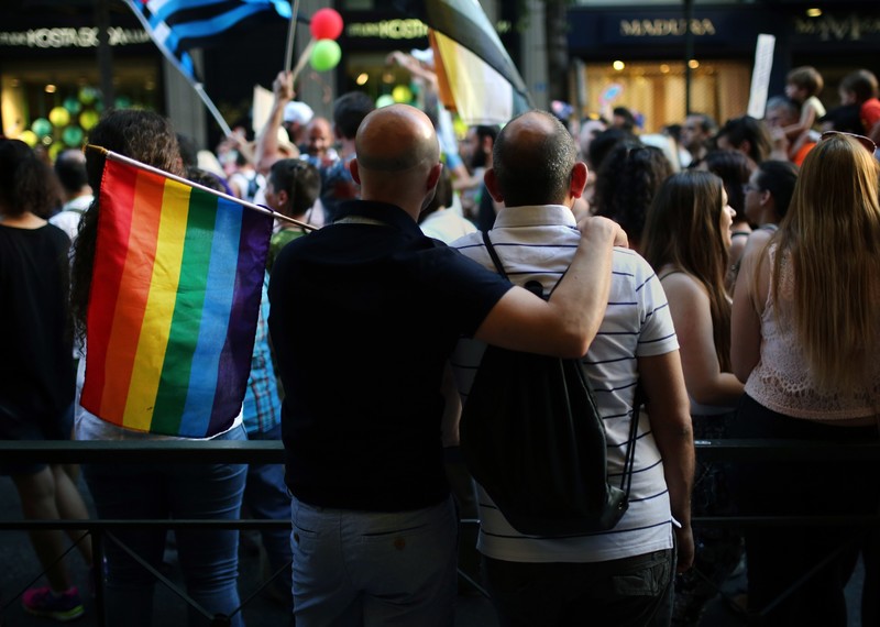 Two men take part in the annual Gay Pride parade in Athens. One has his arm around the other.