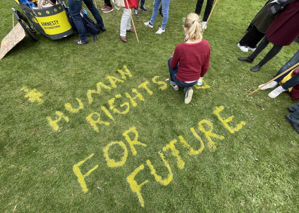 Una activista pinta sobre la hierba las palabras “derechos humanos para el futuro”, Berlín, 2021.