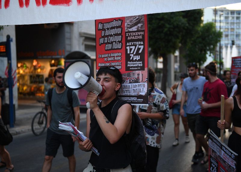 People carry banners and protest against the Pylos migrant ship crash in Athens, Greece.