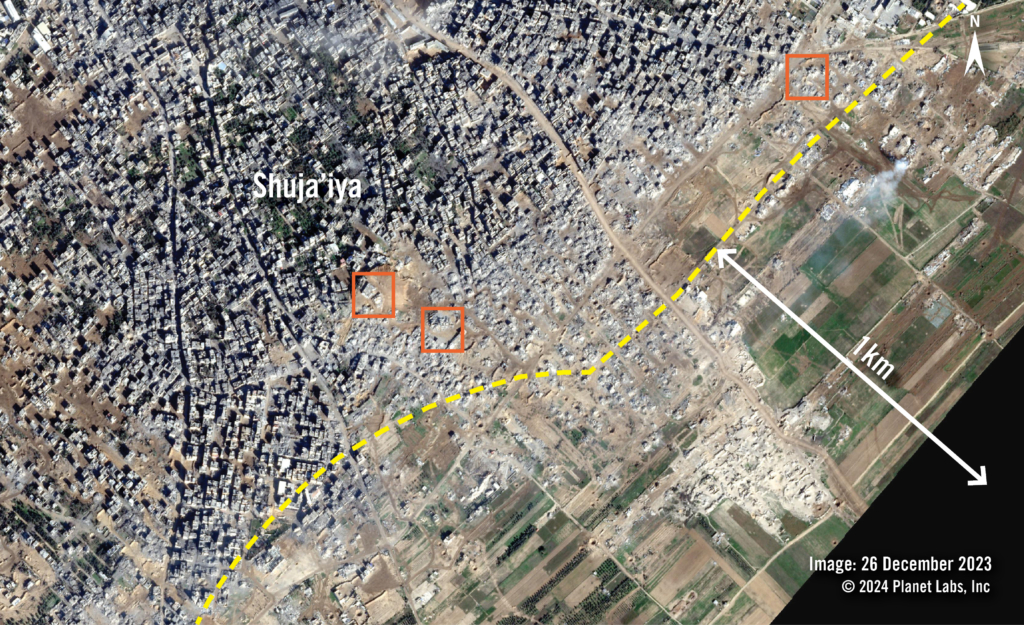 Satellite image show a town after it was destroyed. Red squares highlight the location of two mosques and  schools within a yellow dotted line showing the 1km mark.