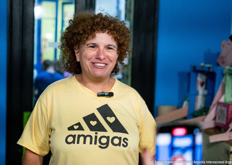 Pierina Nochetti luce sonriente una camiseta amarilla con el lema “amigas”, un juego de palabras con el logotipo de “Adidas”.