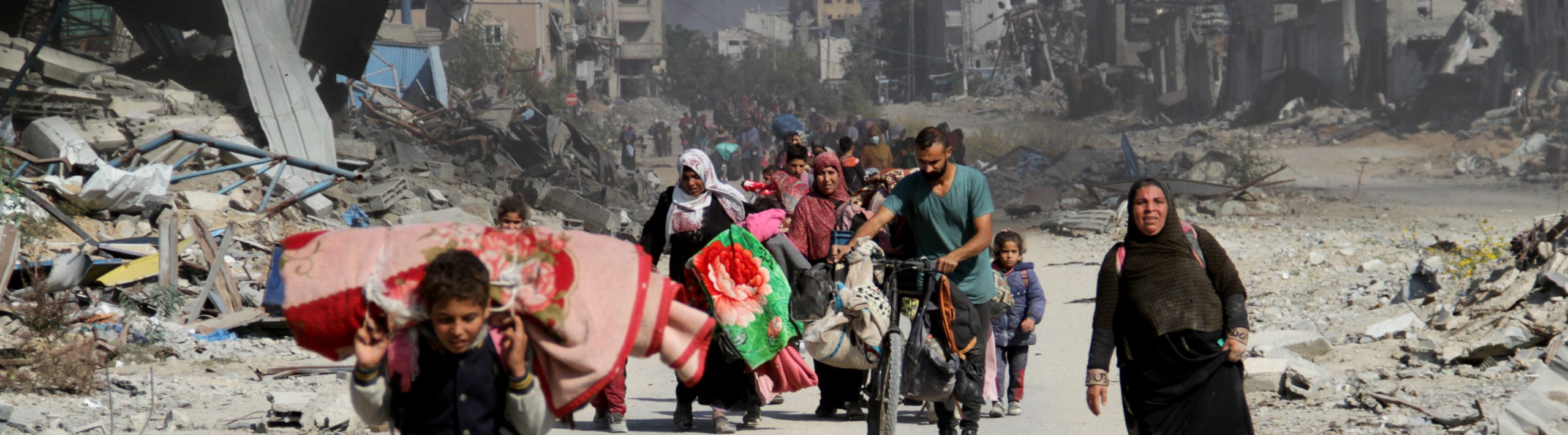 Palestinians carrying essential belongings flee their houses after Israel issued new evacuation orders in the north of the enclave as living and humanitarian conditions deepening due to intense Israeli attacks on Beit Lahia, Gaza Strip on November 05, 2024. Smoke is billowing in the background.