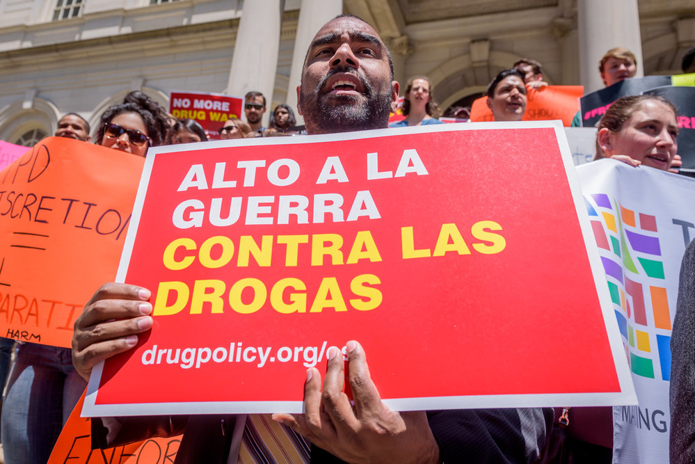Grupo de personas con pancartas ante un edificio gubernamental. El cartel principal a la vista dice “Alto a la guerra contra las drogas”.
