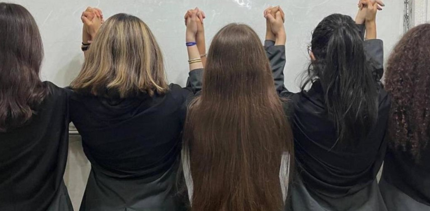 Un grupo de niñas iraníes de espaldas y cogidas de la mano muestran su pelo.