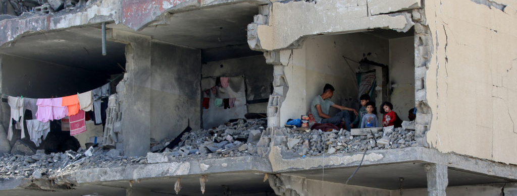 Un hombre palestino y sus hijos sentados en una habitación en ruinas tras la destrucción de un edificio residencial por un ataque aéreo israelí en Rafá, en el sur de la Franja de Gaza, el 22 de mayo de 2024, durante el conflicto en curso entre Israel y el grupo palestino Hamás.