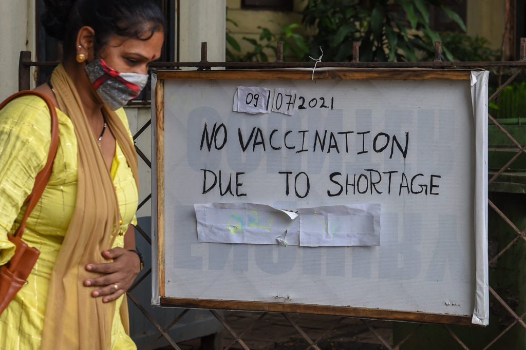 A woman walks past a sign reading 'no vaccination due to shortage'.