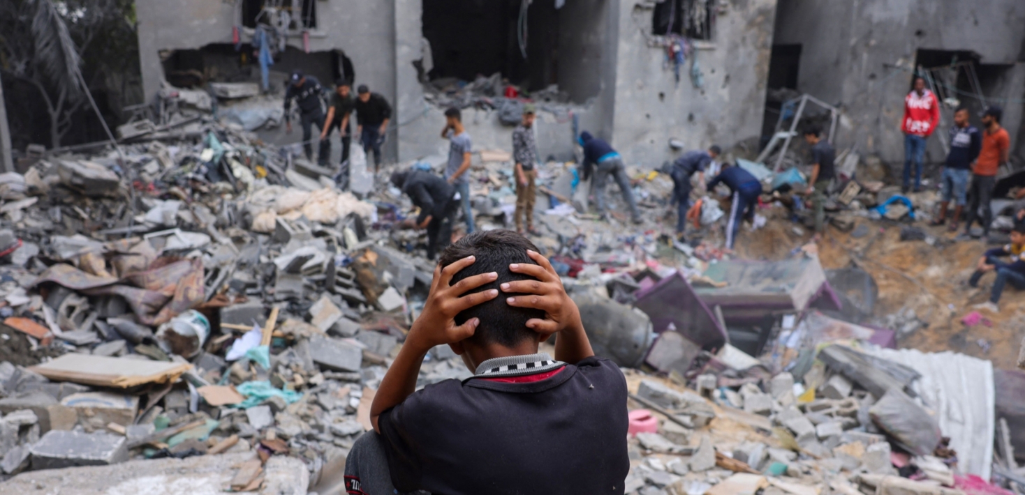 Un enfant se tient la tête en regardant les ruines d'un bâtiment