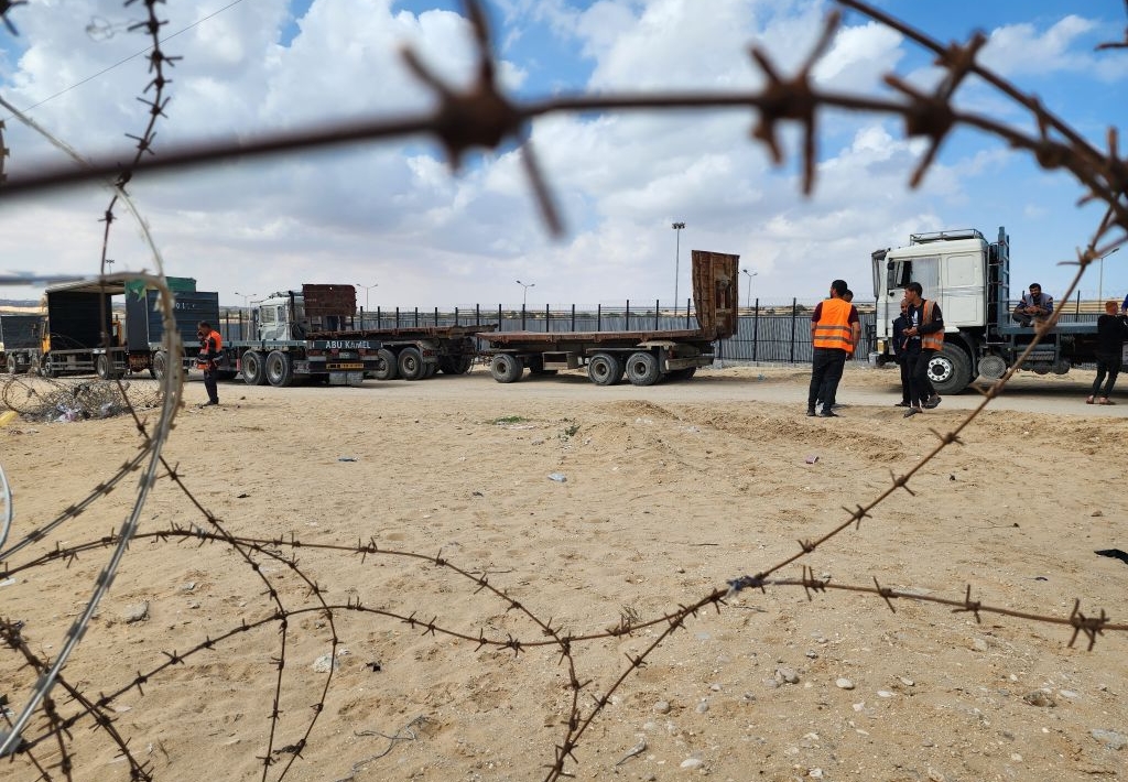 Un camion d'aide humanitaire au point de passage de Rafah vu à travers du barbelé.