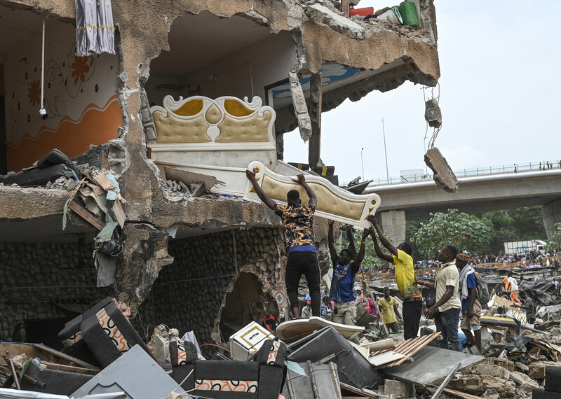 Des résidents sortent un lit d'un bâtiment partiellement détruit dans le quartier de Boribana à Abidjan le 23 février 2024